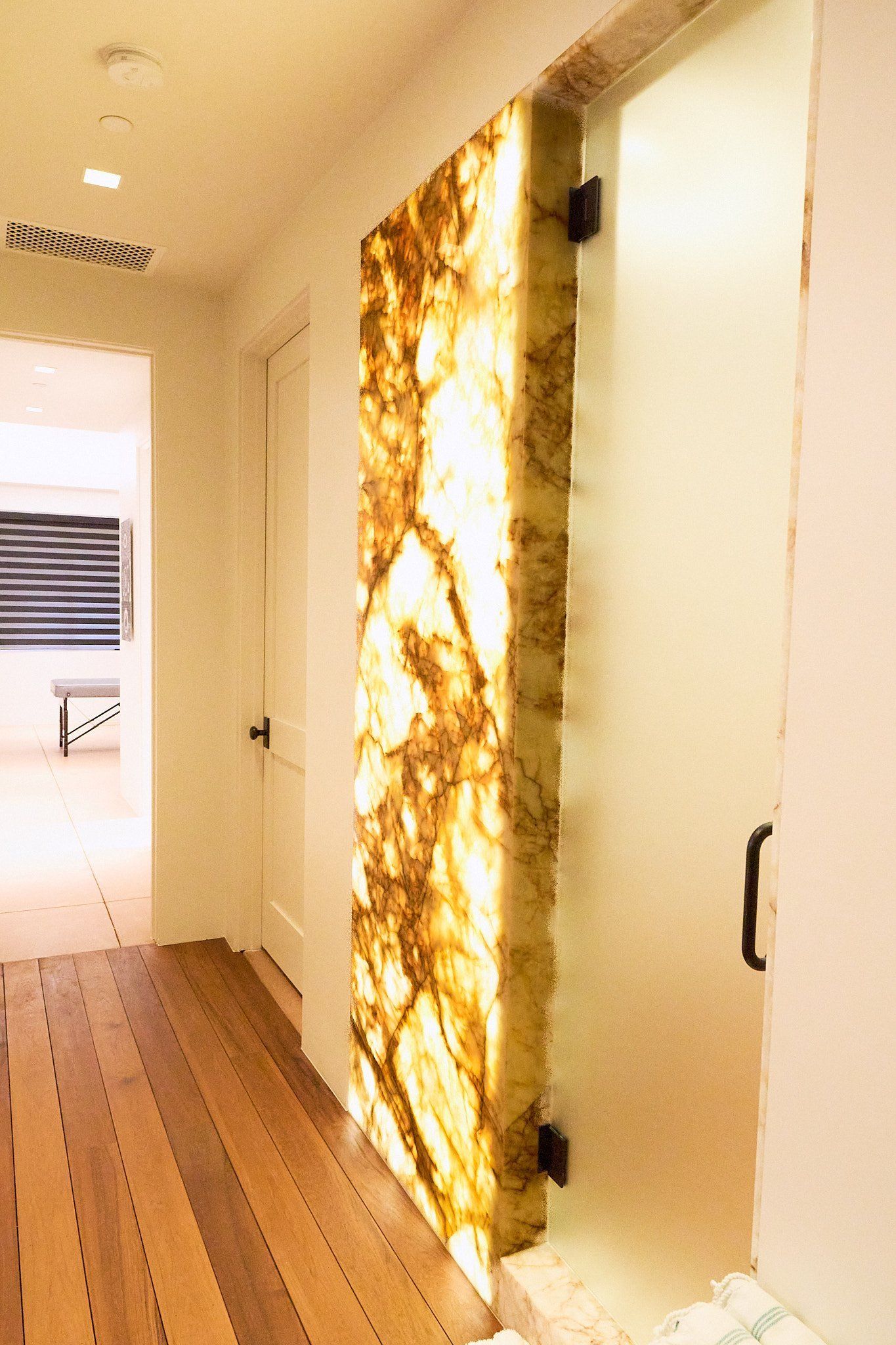 A hallway with a marble wall and a wooden floor.