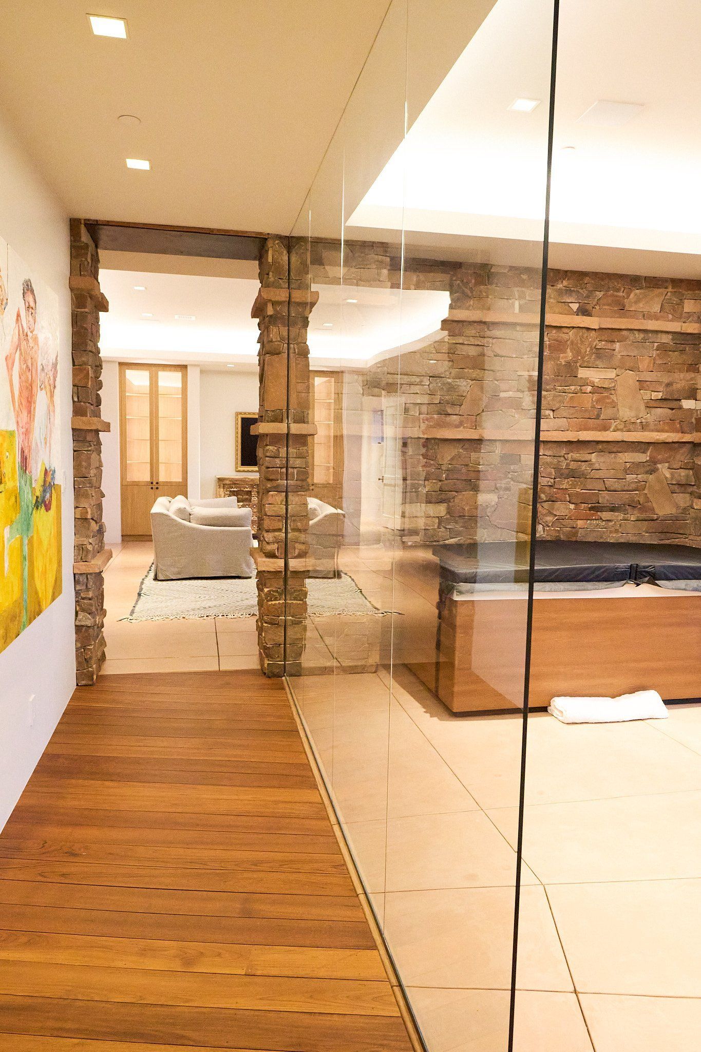 A hallway with wooden floors and a glass wall leading to a living room.
