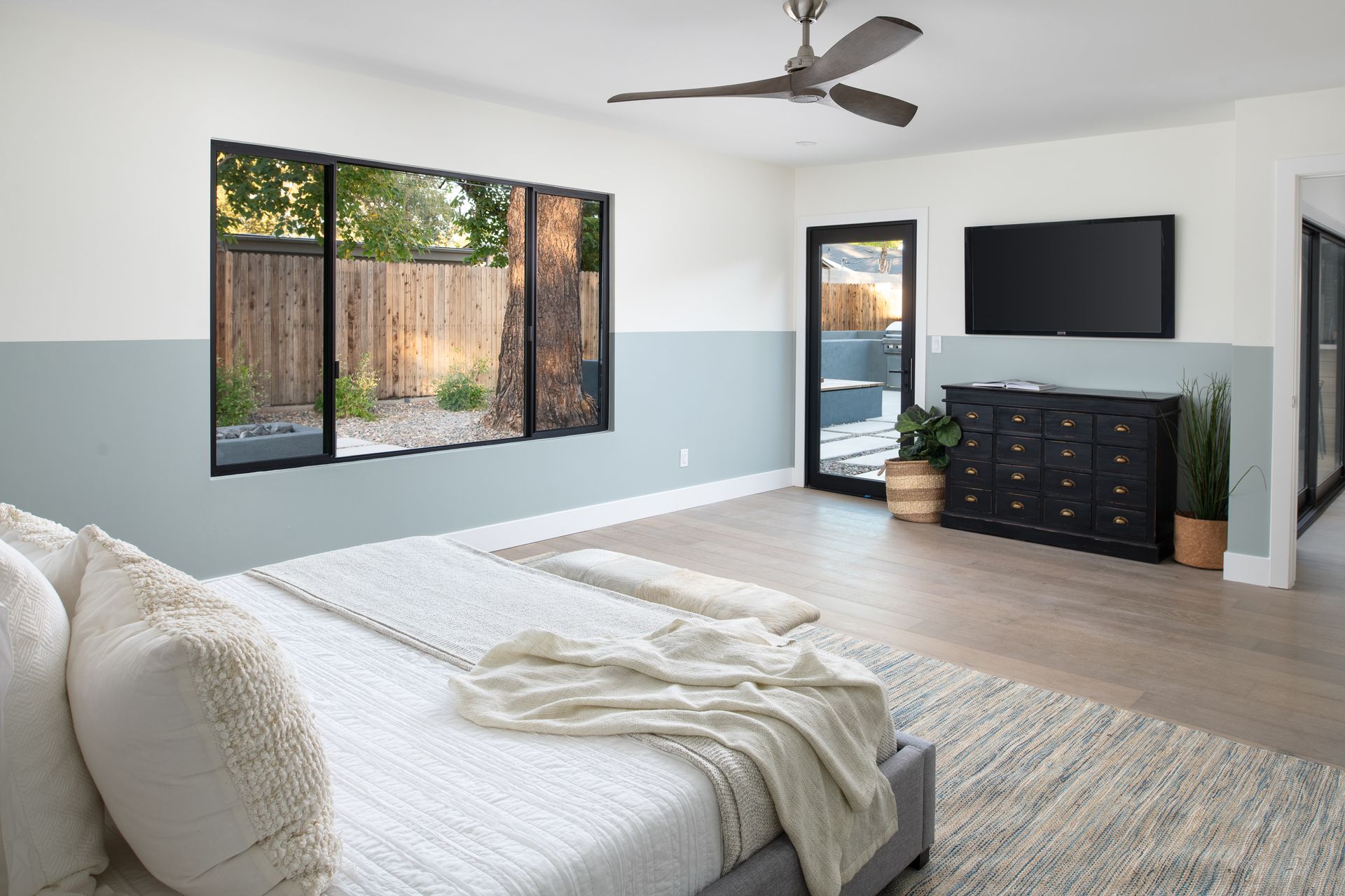 A bedroom with a bed , dresser , television and ceiling fan.
