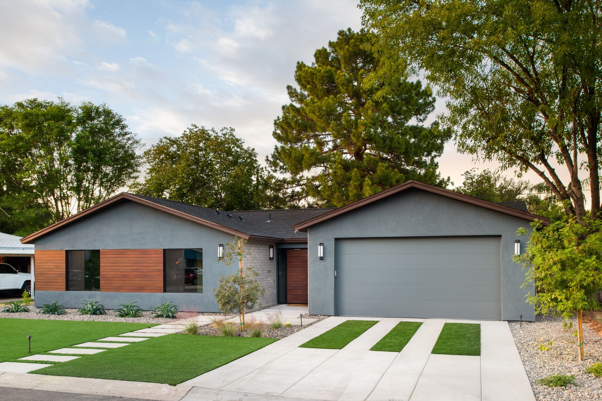 A gray house with a concrete driveway leading to it