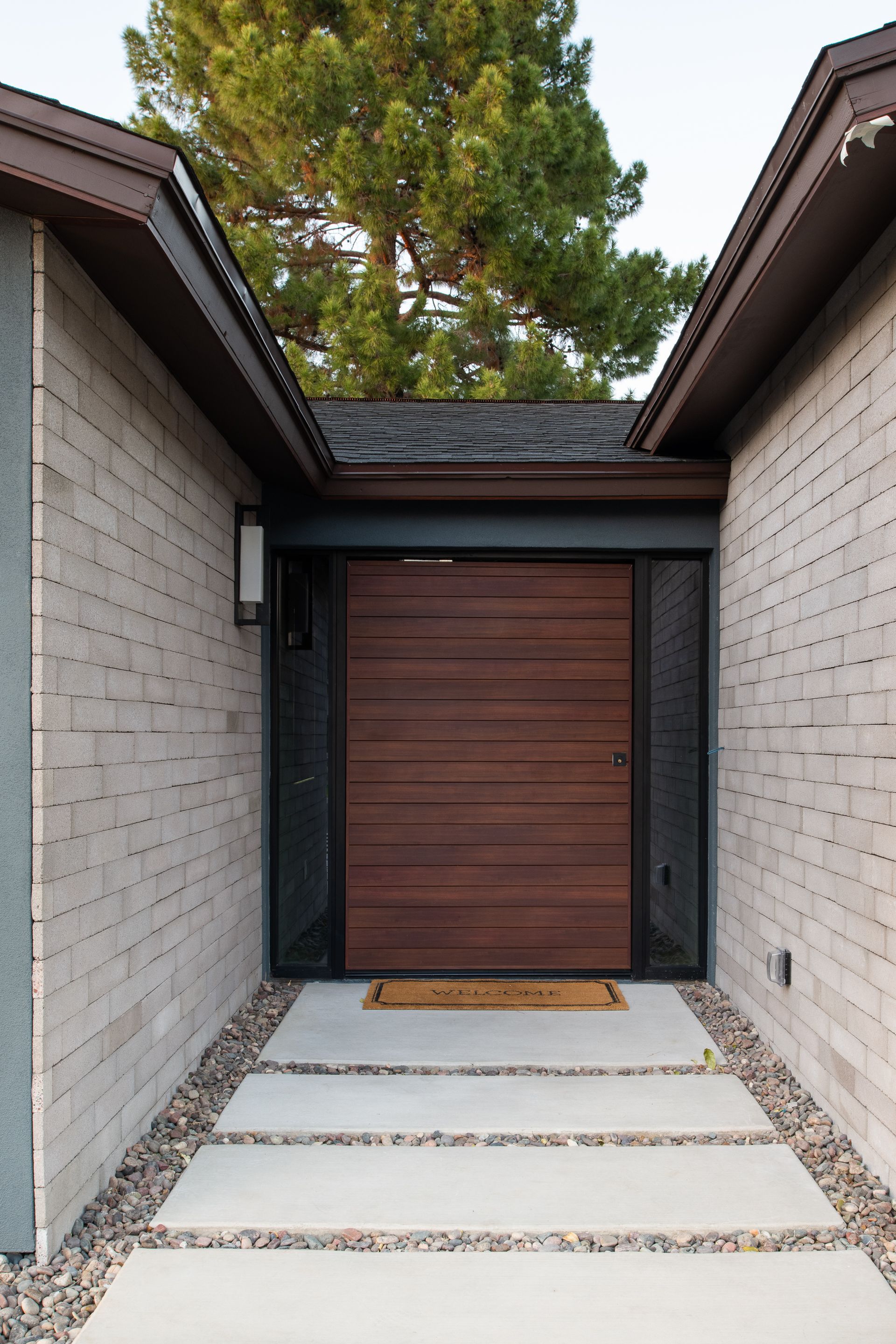 A brick house with a wooden door and a welcome mat