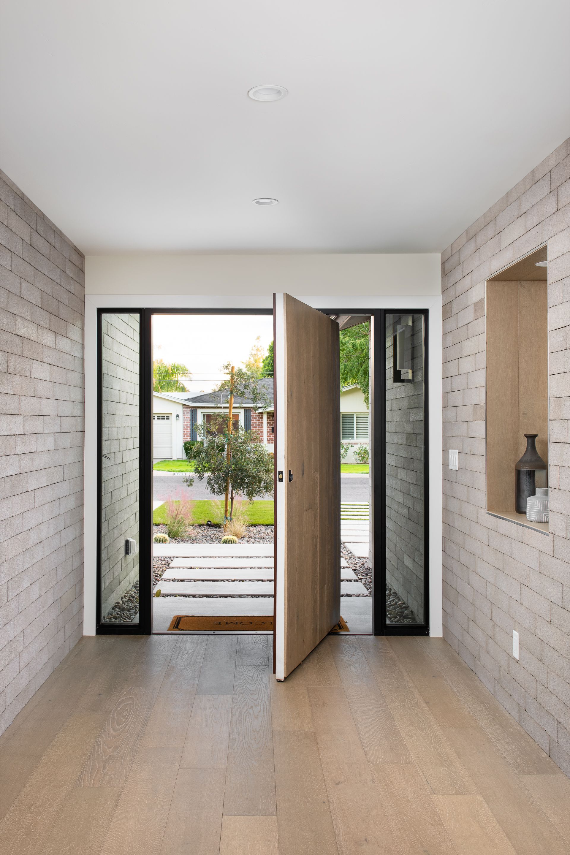 A hallway with a door open and a brick wall.