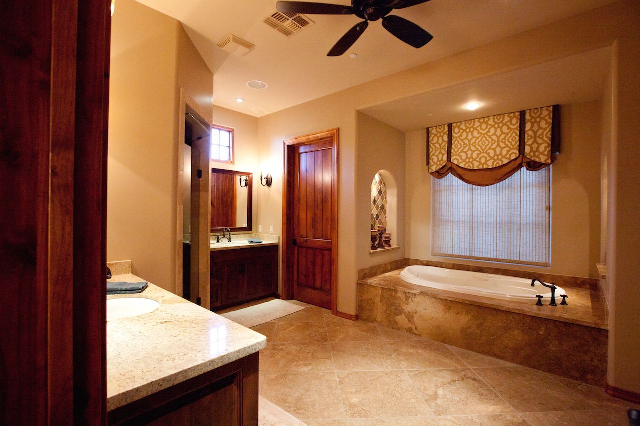 A bathroom with a tub and a ceiling fan