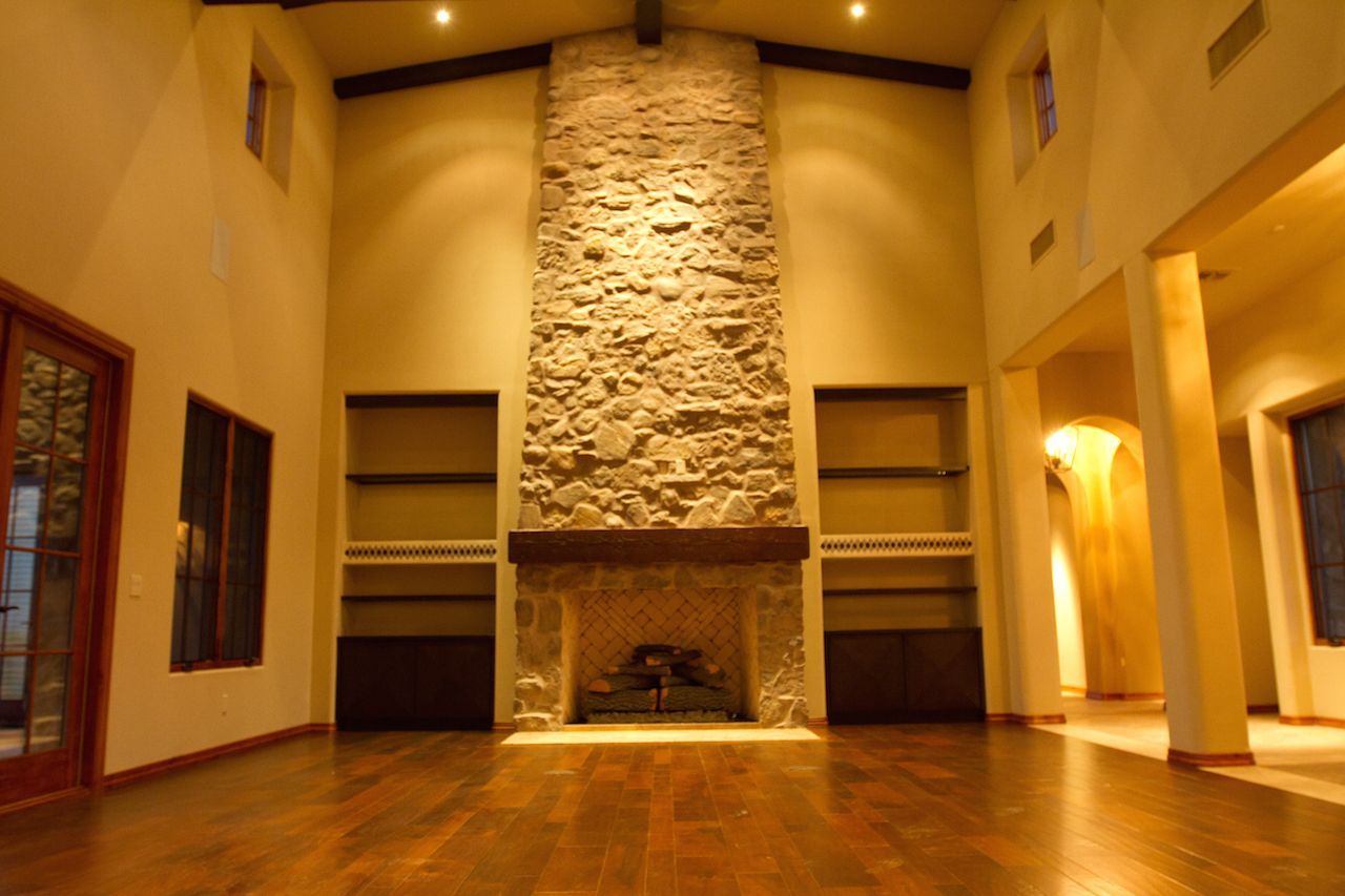 An empty living room with a large stone fireplace
