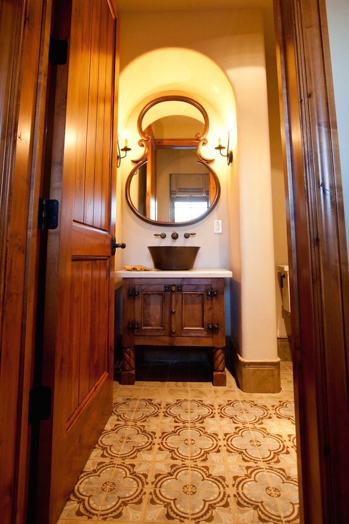 A bathroom with a sink , mirror and wooden cabinets.