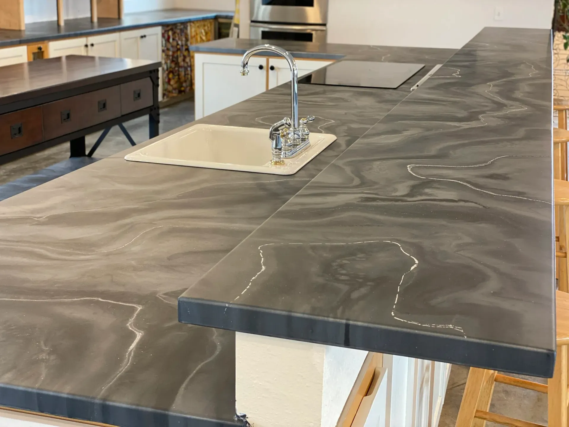 Gray and white marbled countertop with sink and faucet in kitchen setting.