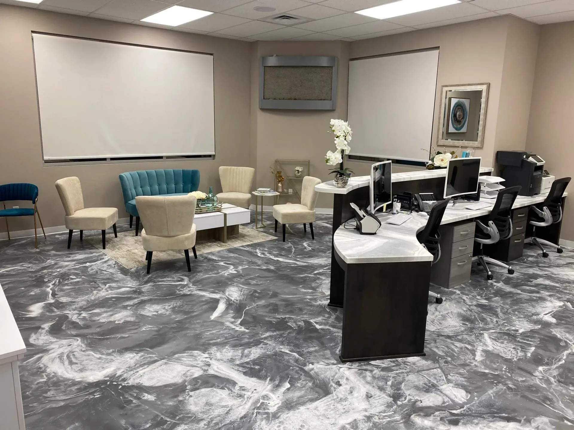 Reception area with reception desk and seating; gray marble-look floors, white and gray accents.