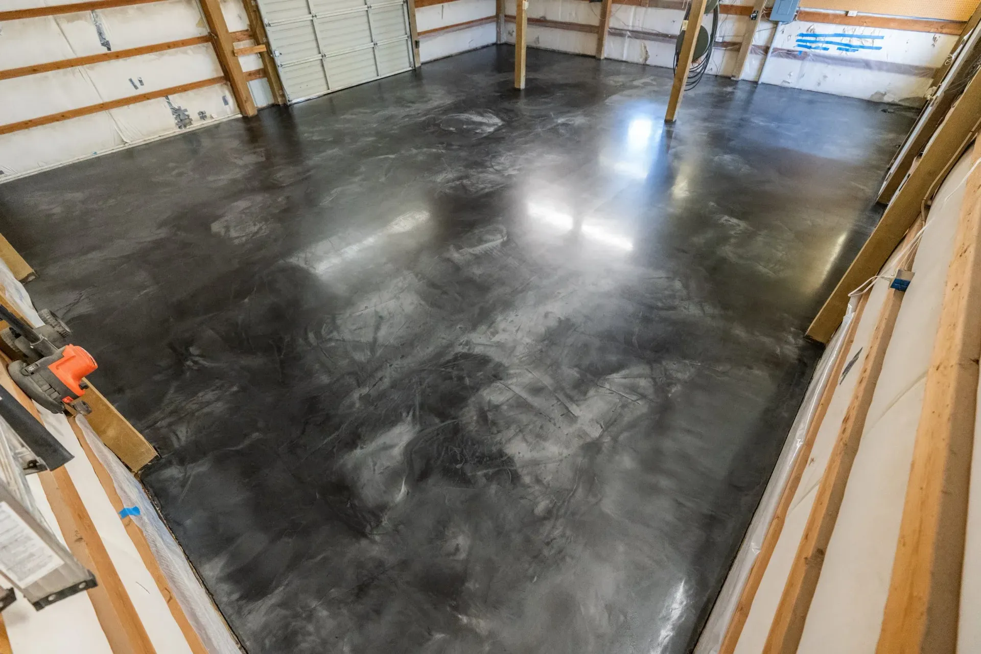 Gray, polished concrete floor inside a wooden structure with wood beams and white insulation.