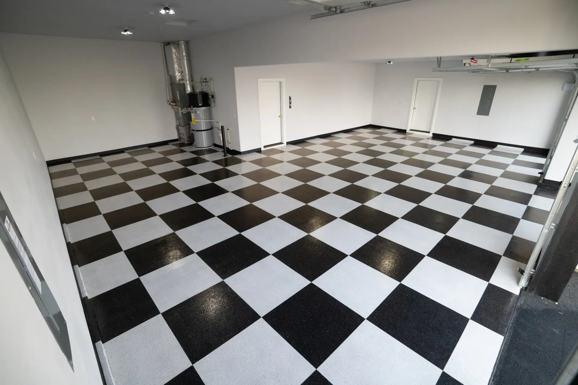 Spacious garage with black and white checkered floor. Walls are gray and doors are white.