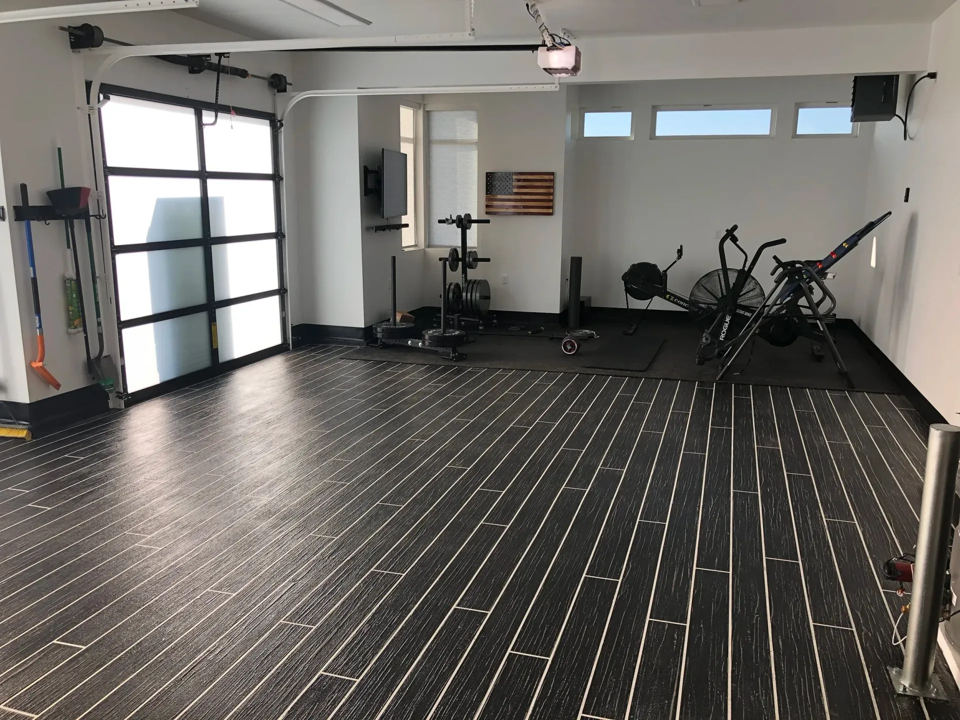 Garage gym with black flooring and exercise equipment.