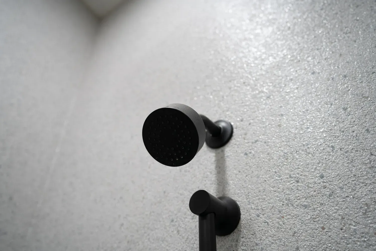 Black showerhead on a textured gray wall.