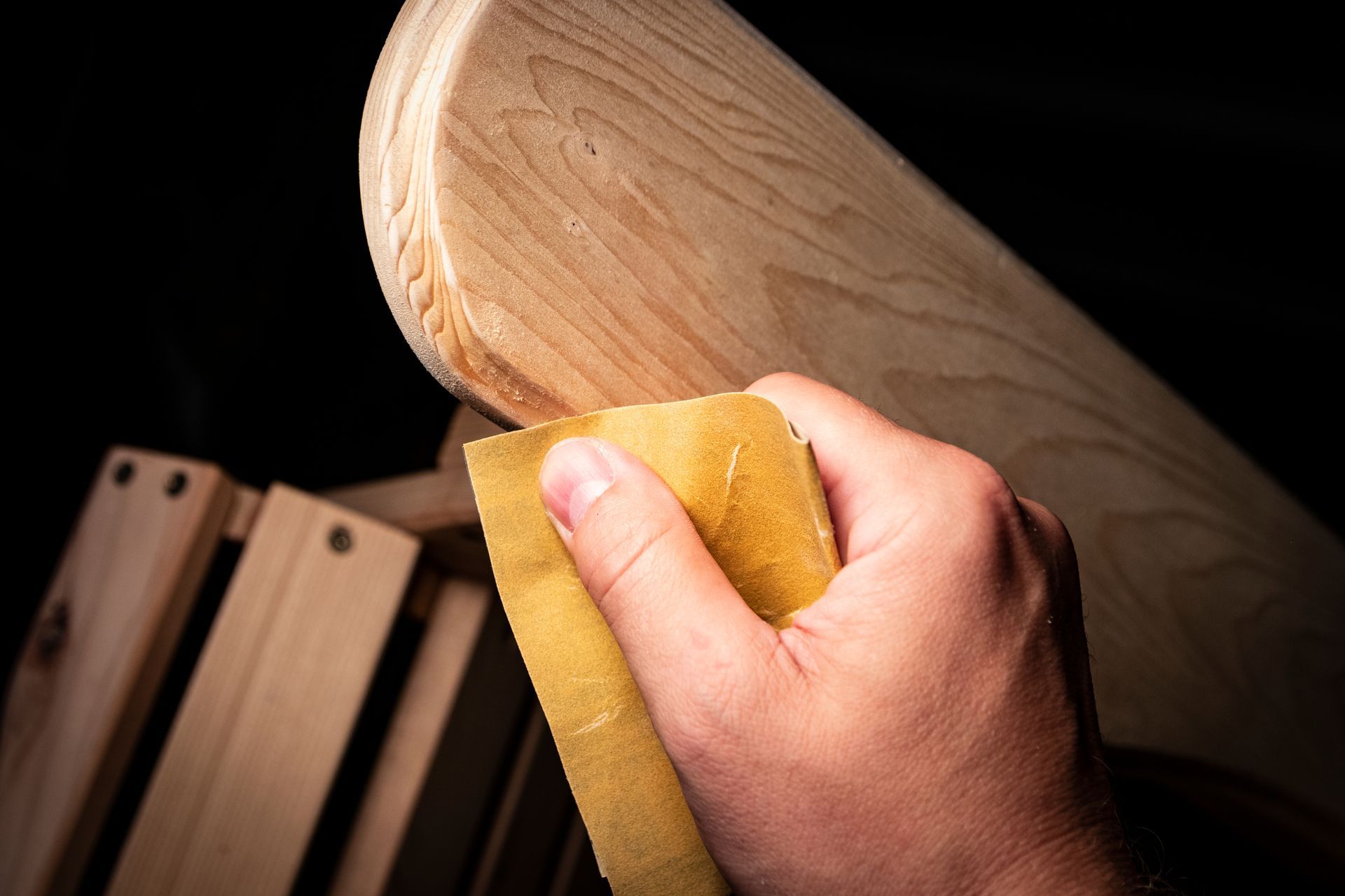 Une personne ponce un morceau de bois avec du papier de verre.