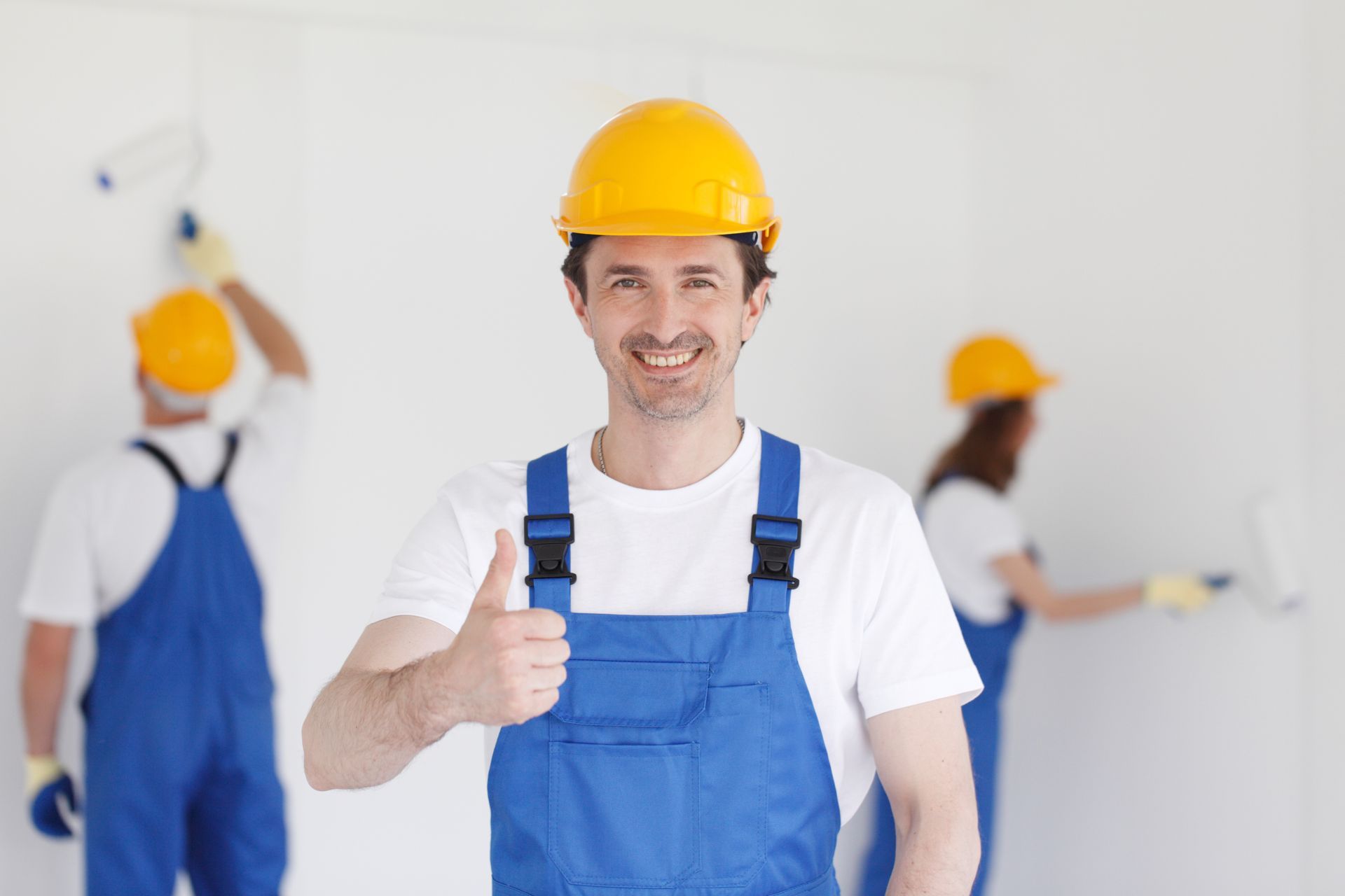 Un homme en salopette et casque de sécurité lève le pouce.