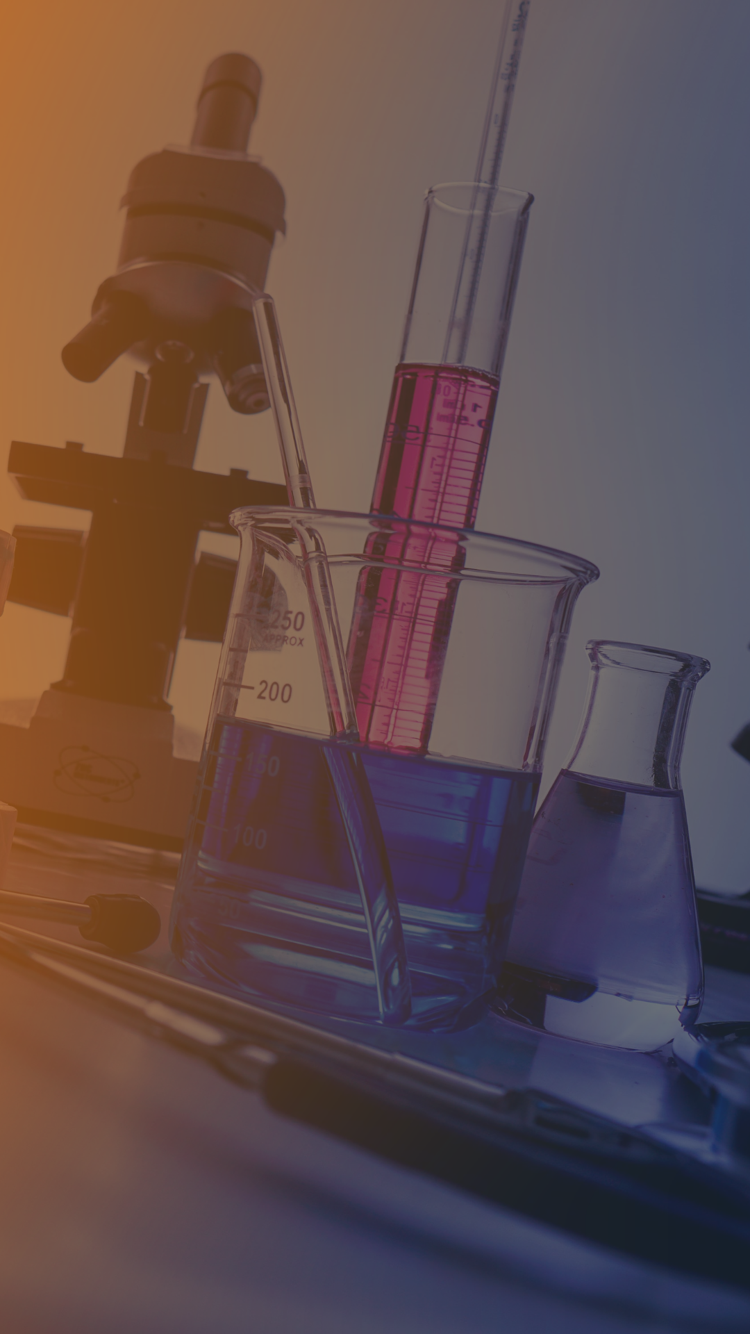 A microscope, beakers, and test tubes are sitting on a table in a laboratory.