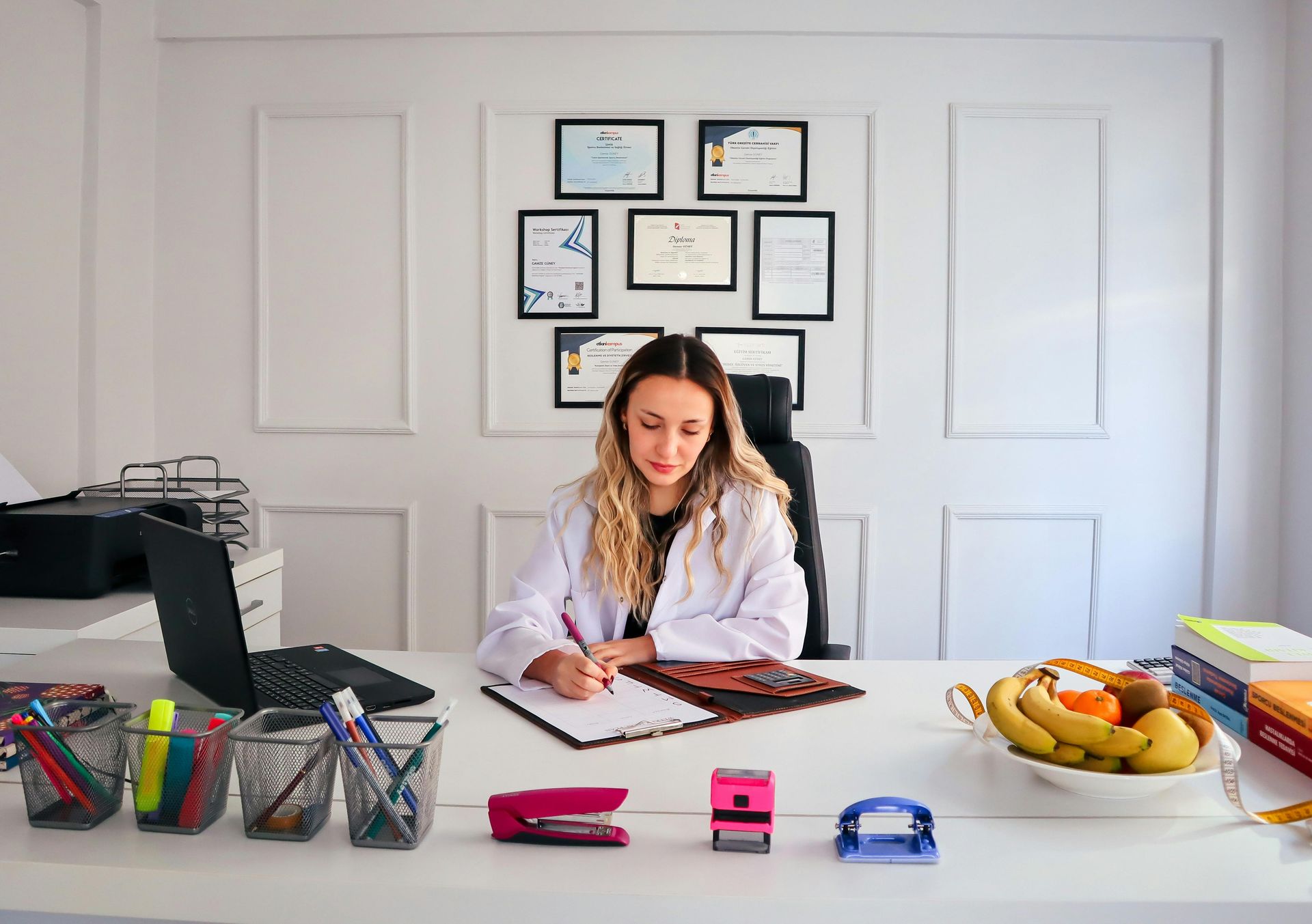 Doctor filling out paperwork with degrees behind her