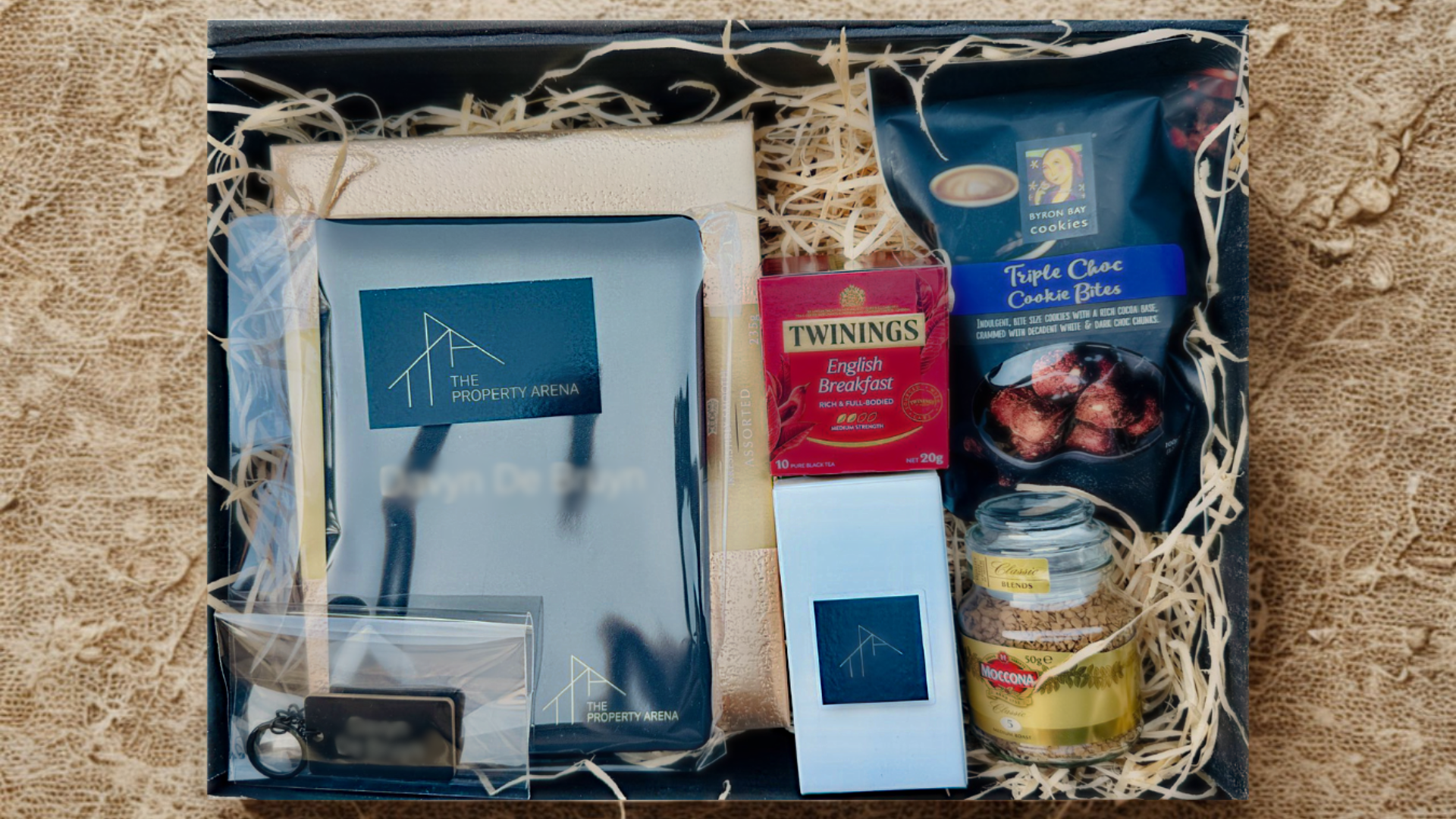 Open black gift box with luxury corporate items on linen background, styled for EOFY B2B gifting.