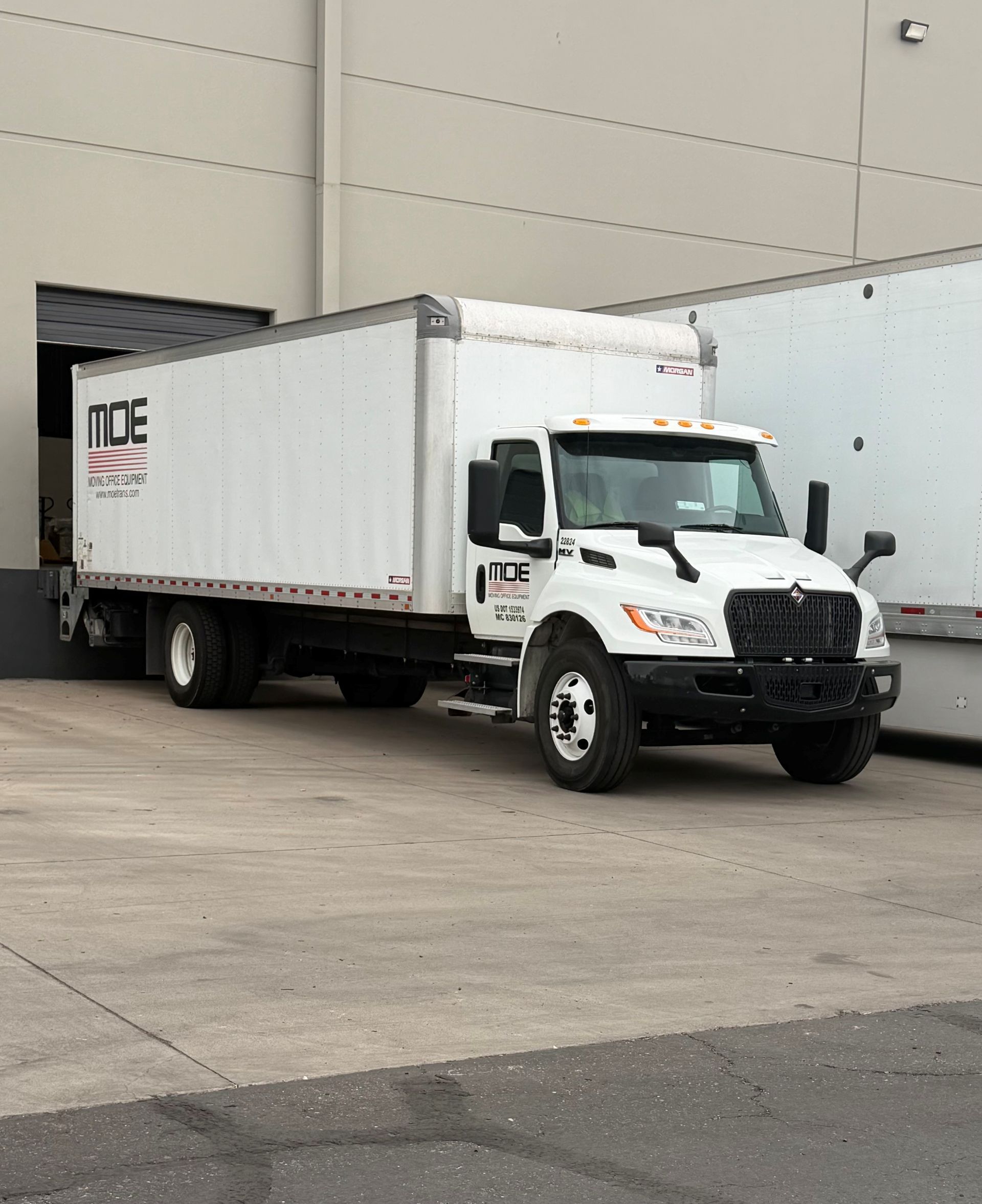 White box truck parked beside a warehouse loading dock