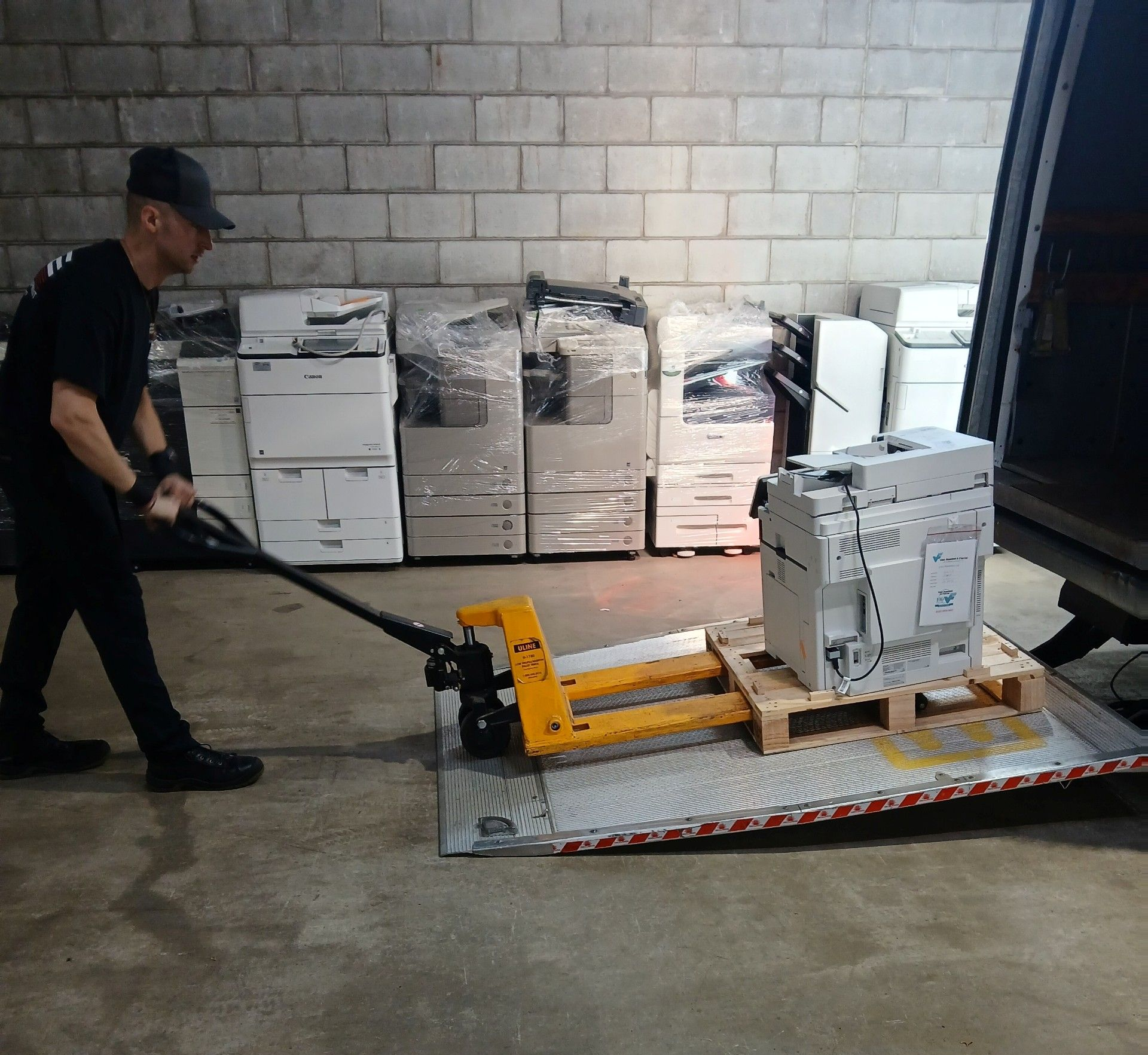 Worker pulling a pallet jack carrying stacked boxes in a warehouse
