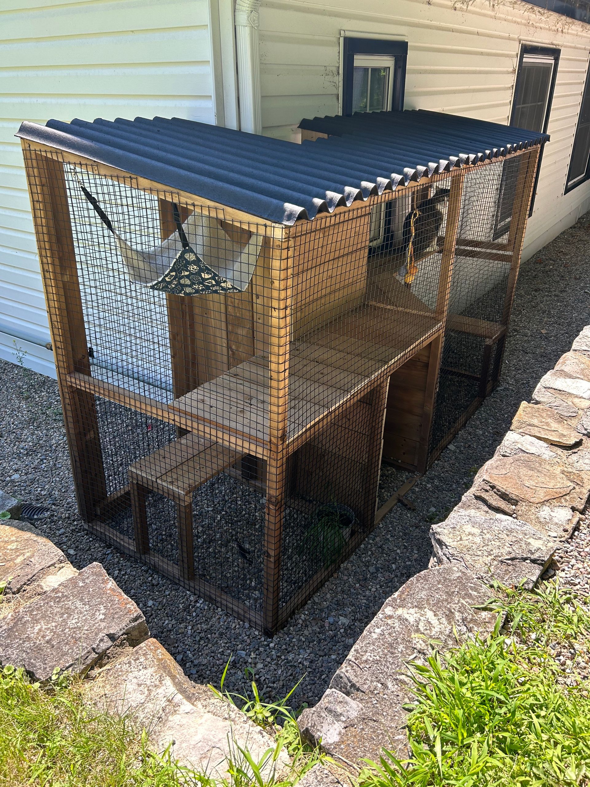 A wooden cage with a black roof is sitting in front of a house.