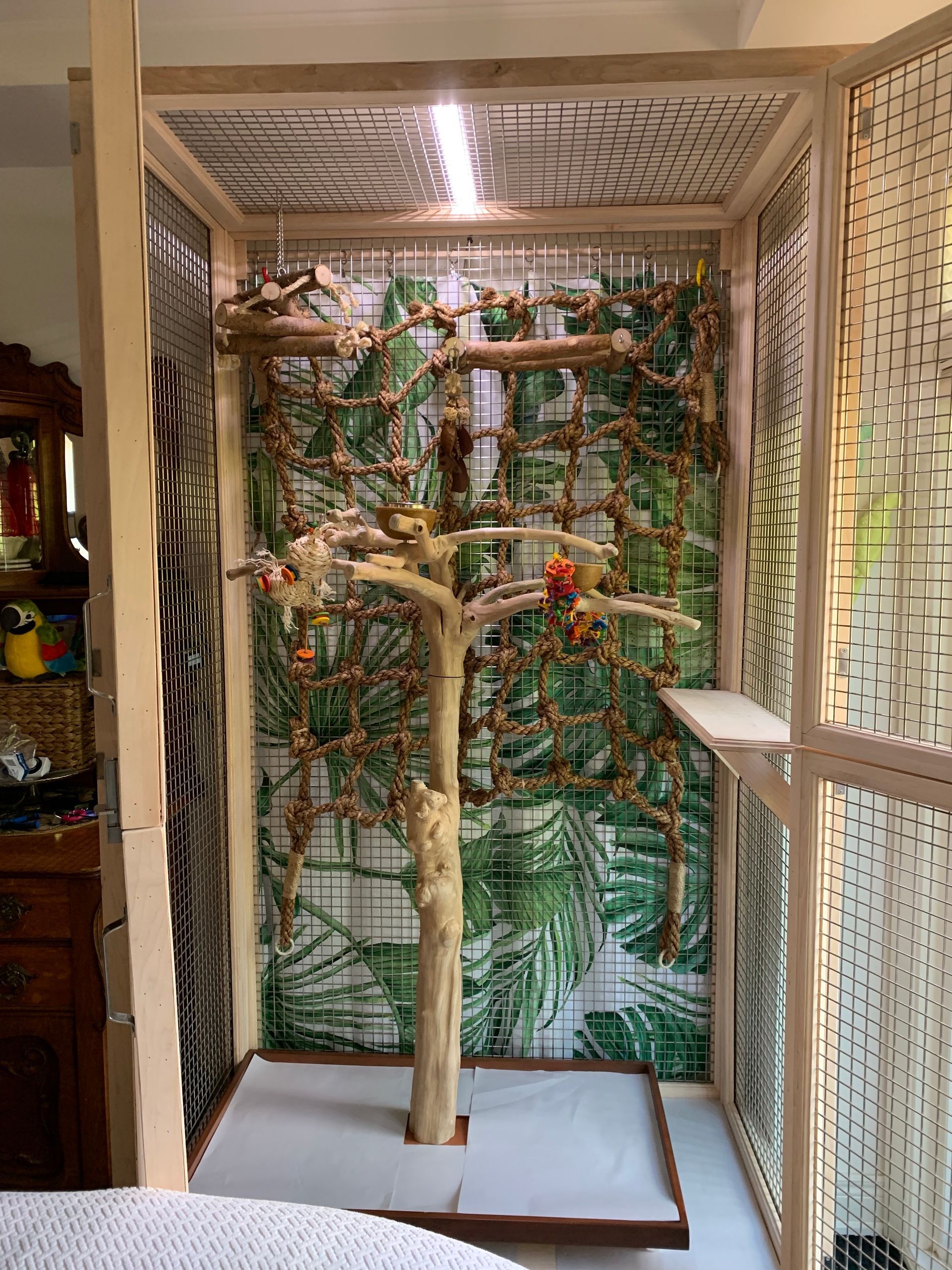 A bird cage with a tree in the middle of it.