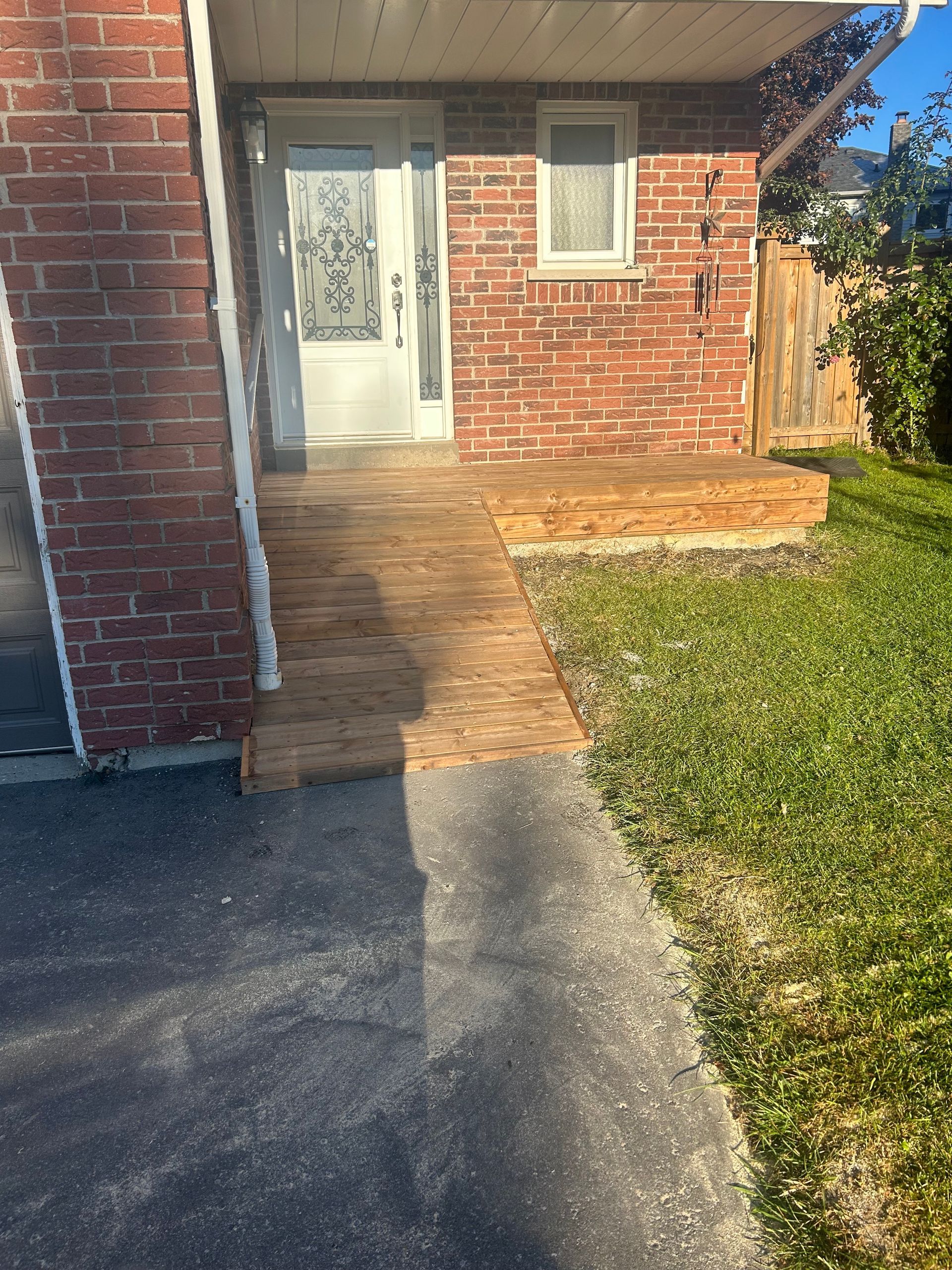A brick house with a concrete walkway leading to the front door.