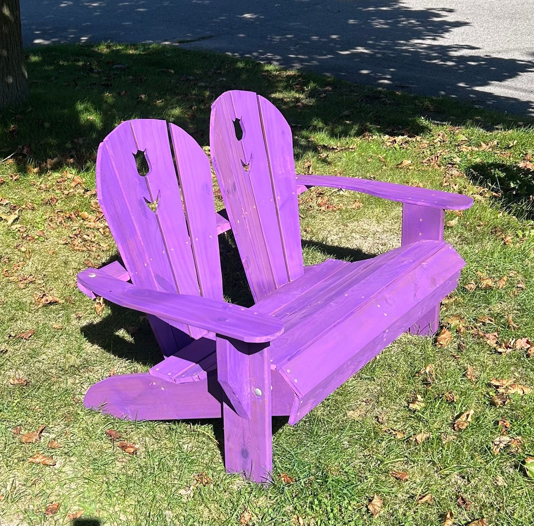 A purple adirondack chair is sitting in the grass