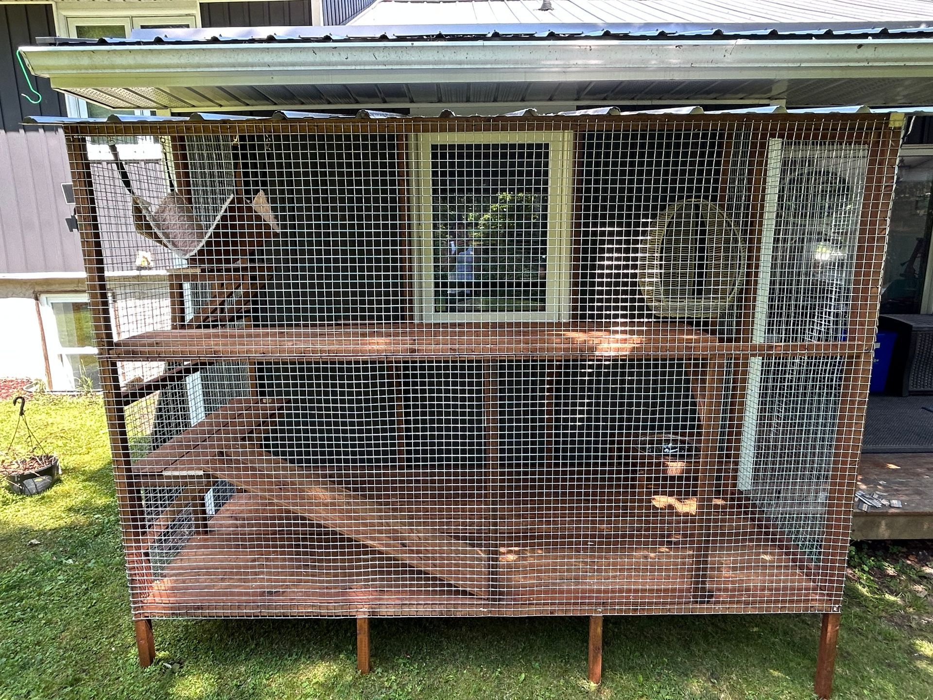 A large cage is sitting in the grass in front of a house.