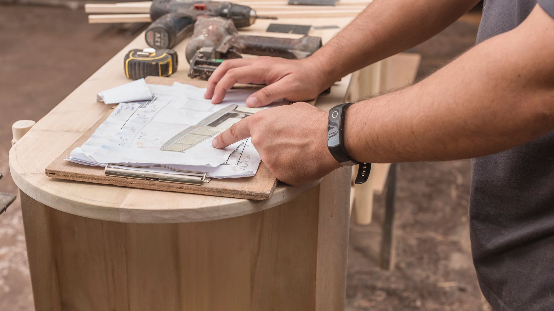 A man is working on a wooden table in a workshop.