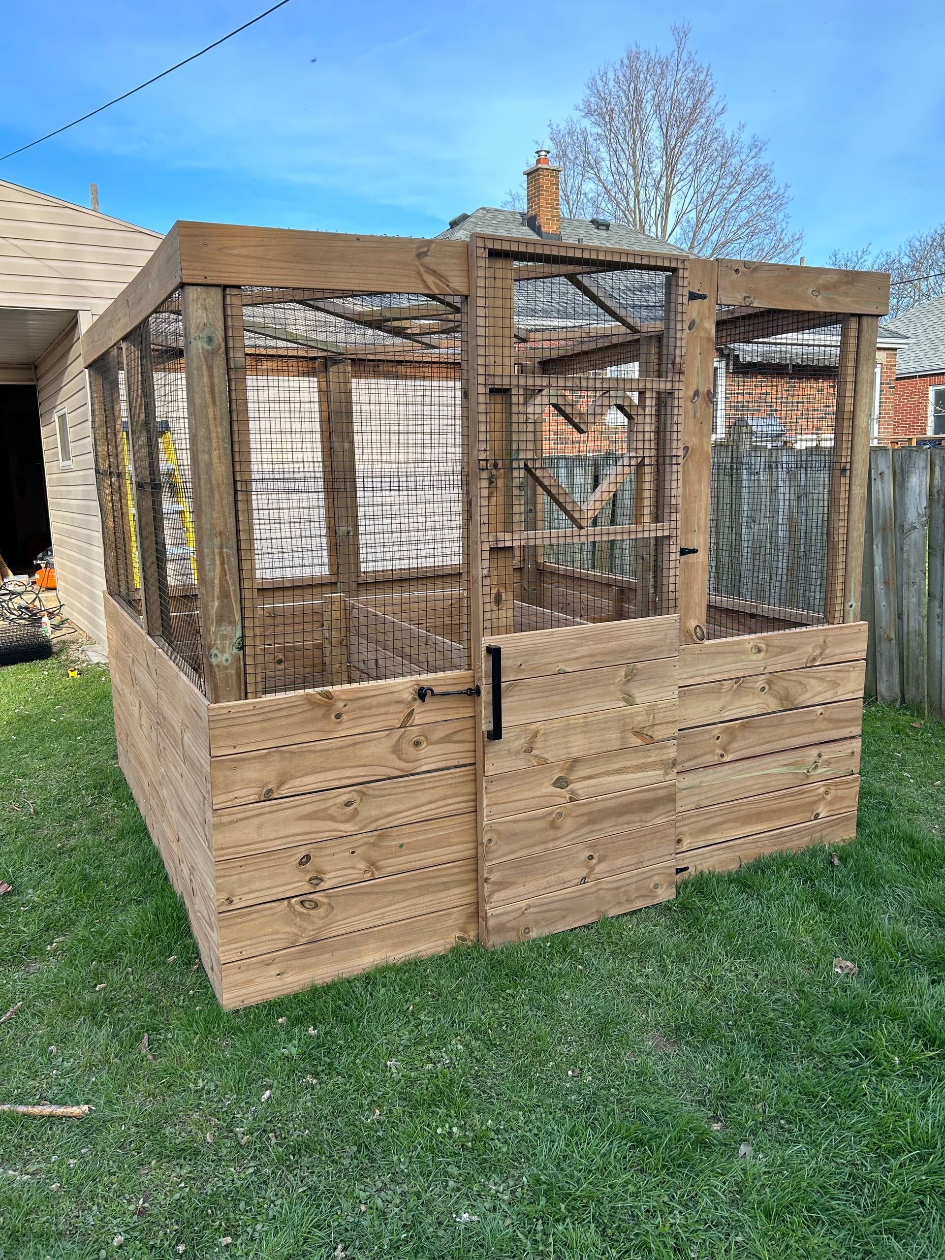 A wooden cage is sitting on top of a lush green lawn.