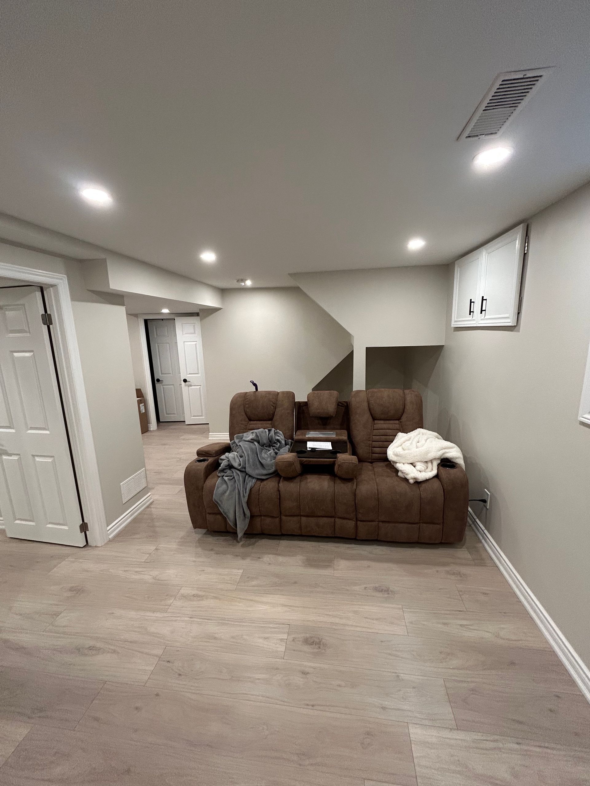 A chicken coop with a white door and windows is sitting in the dirt.