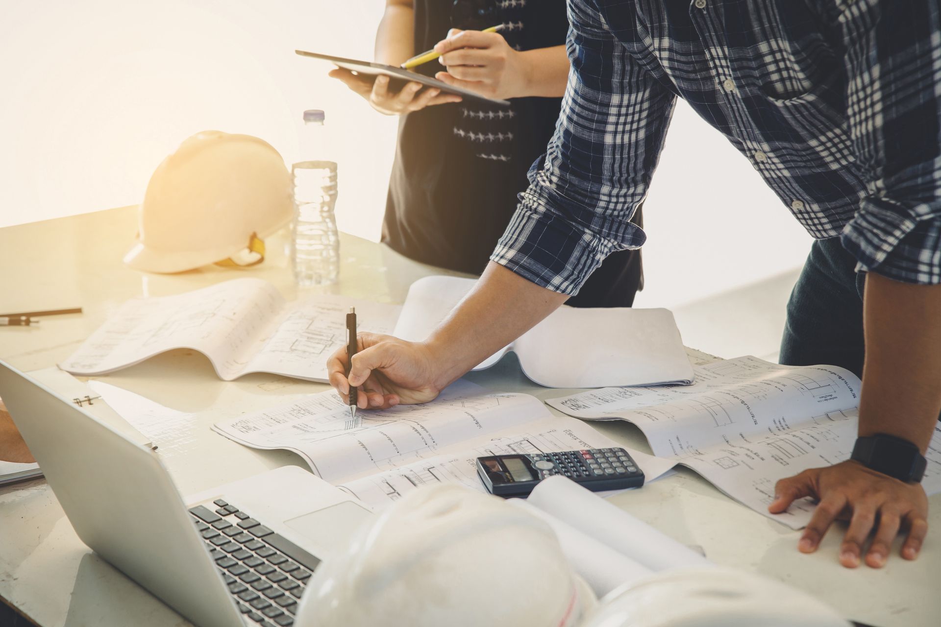 A group of people are standing around a table looking at blueprints.