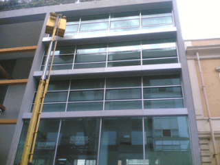 Pulizia di vetrate di un palazzo con macchinari appositi