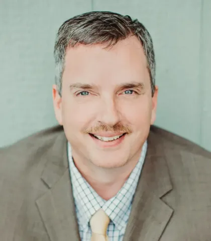A man in a suit and tie is smiling for the camera.