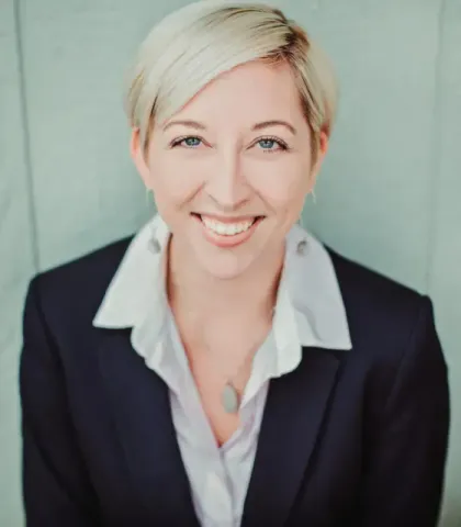A woman in a suit and white shirt smiles for the camera