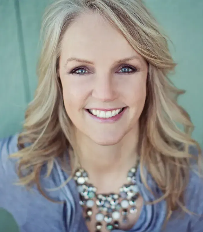 A woman wearing a necklace is smiling for the camera
