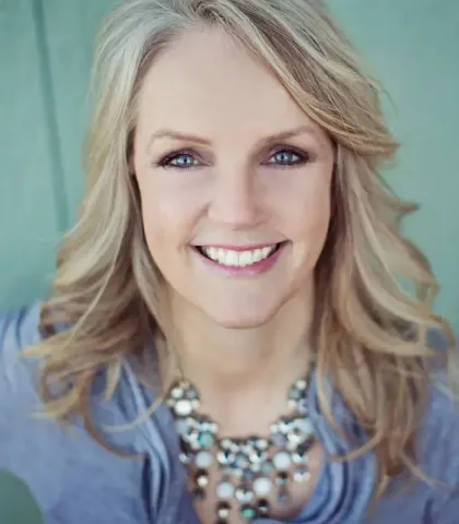 A woman wearing a necklace is smiling for the camera