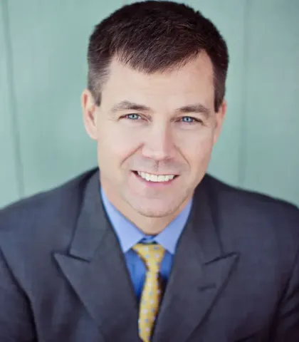 A man in a suit and tie is smiling for the camera.