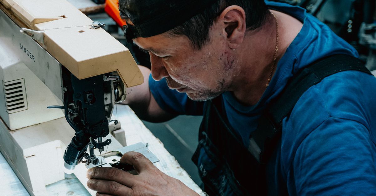 Un hombre utiliza una máquina de coser y trabaja de cerca sobre una tela en un taller.