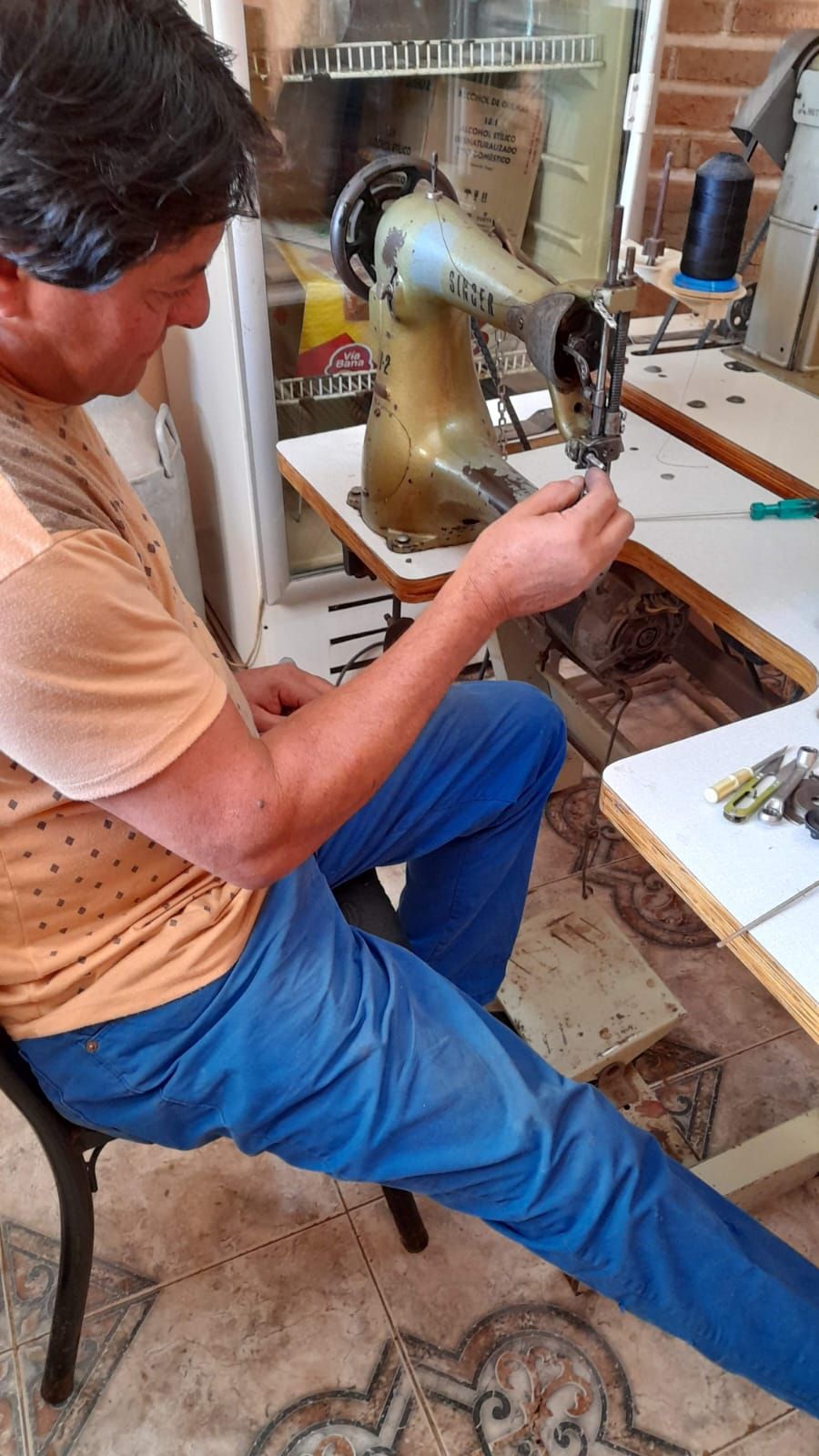 Una persona se agacha junto a una escultura de bronce, trabajando en su cabeza y brazo en un estudio.