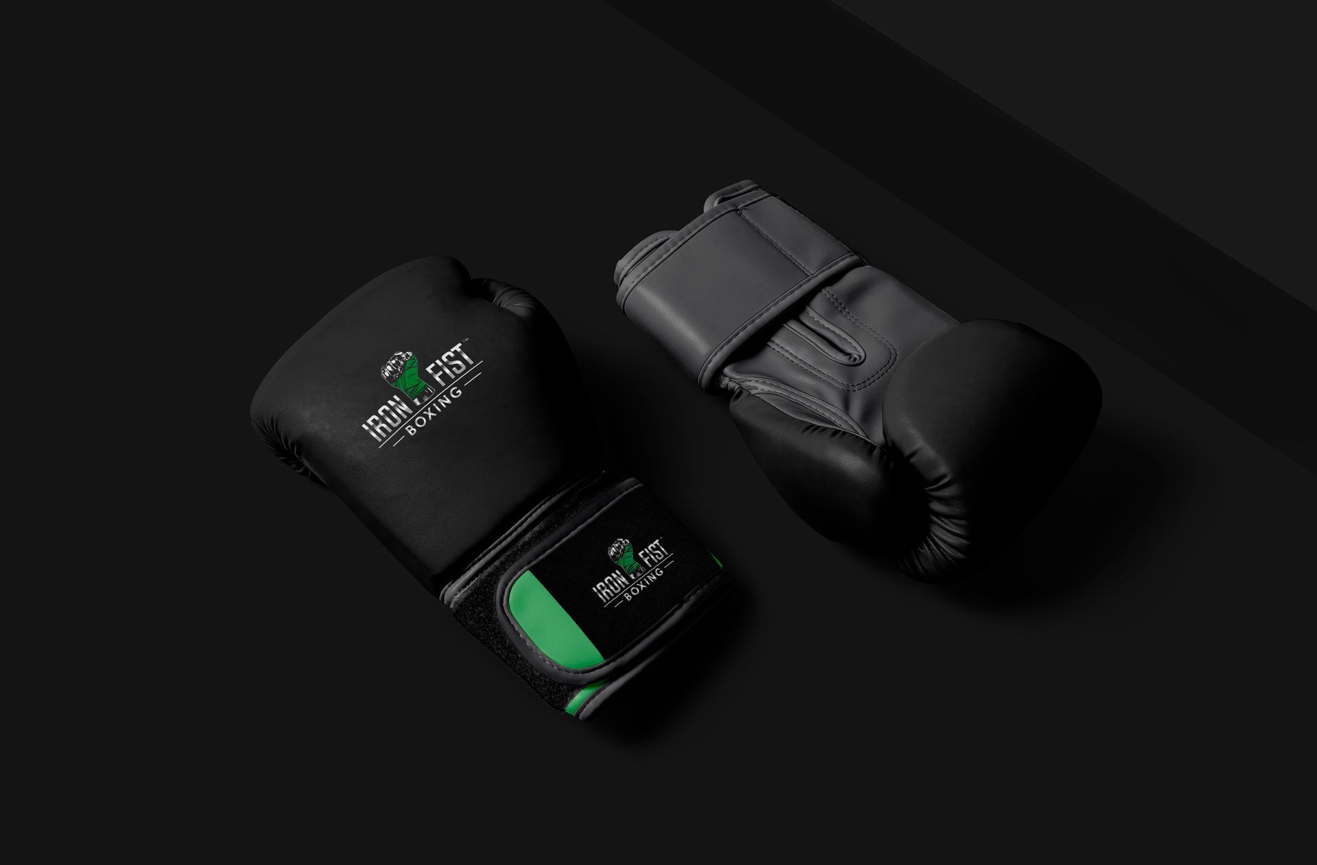 a pair of black boxing gloves with the Irron fist boxing logo printed are sitting on a black surface