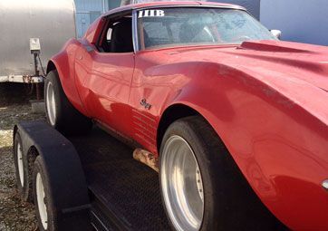 A red corvette is sitting on top of a trailer.