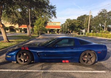 A blue sports car is parked in a parking lot.