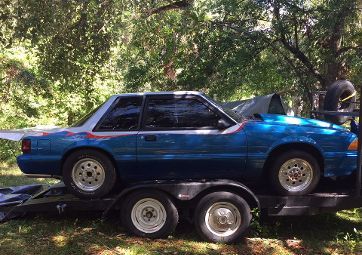 A blue car is sitting on top of a trailer.