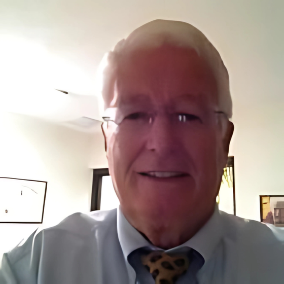 A man wearing glasses and a tie smiles for the camera