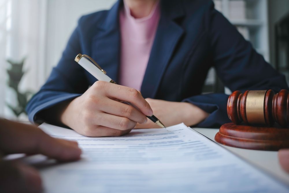 A woman is sitting at a table writing on a piece of paper.