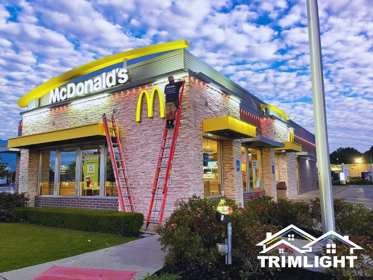 McDonald's building with a worker on a ladder installing lights. Evening setting.