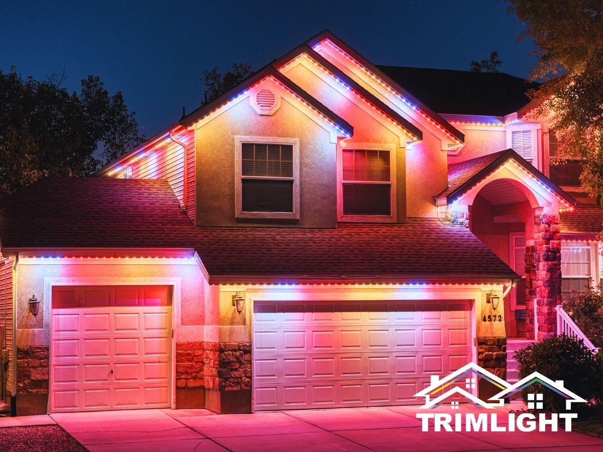 House with colorful lights along the roof and garage doors at night.