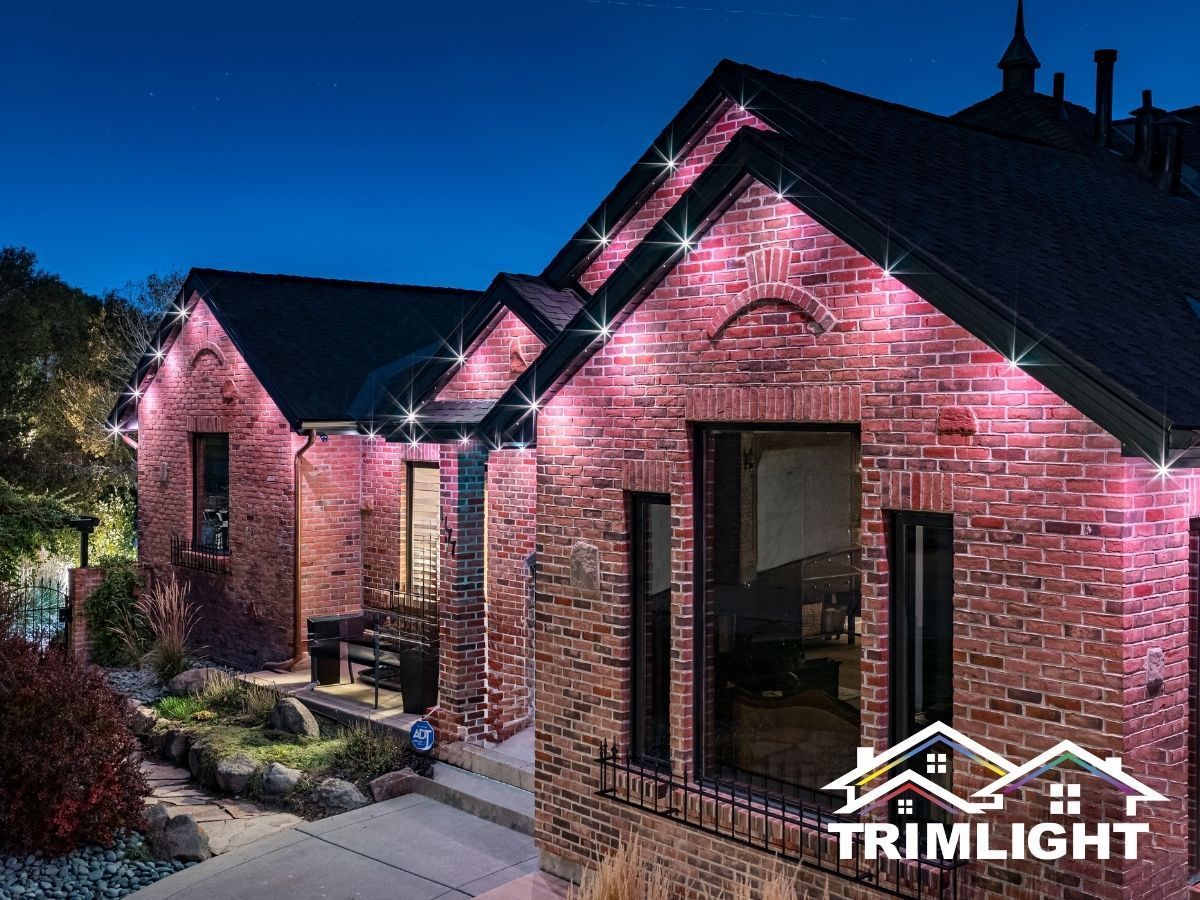 Brick house illuminated with pink lights along the roofline, against a dark blue sky.