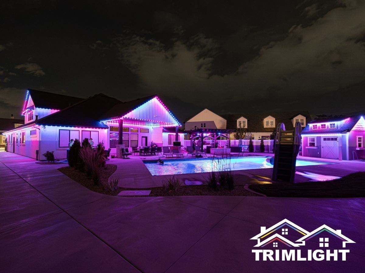 House with pink and blue Trimlight, pool lit up at night.