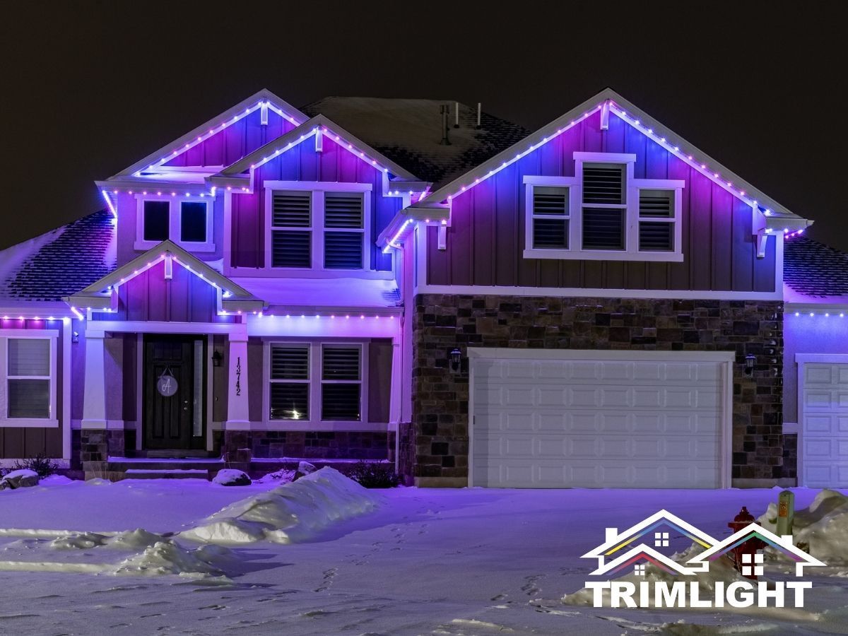 House with blue and purple Christmas lights in the snow.